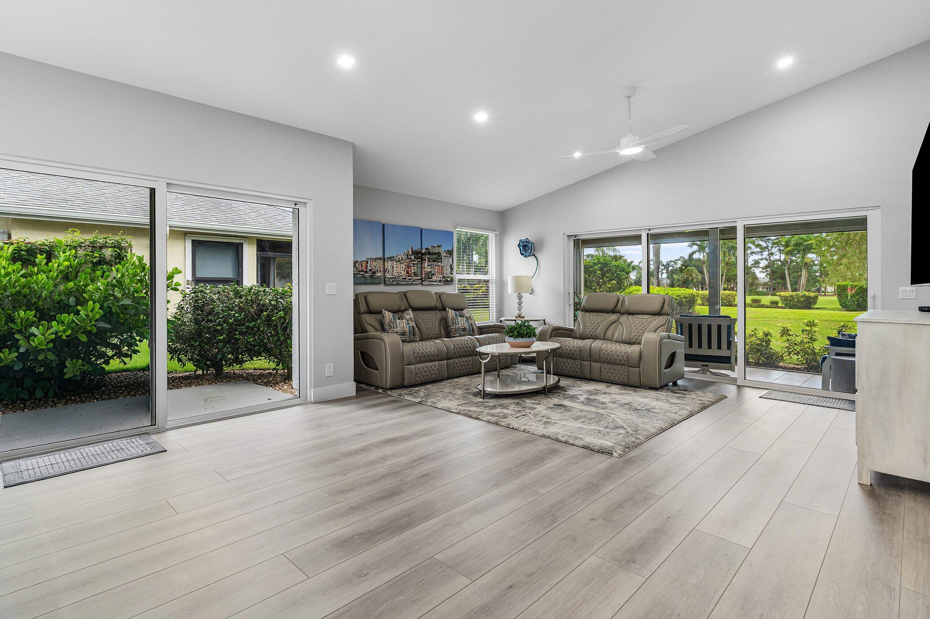Living room at 13320 Touchstone Court with vaulted ceiling and stacking sliding glass doors opening to the covered lanai and golf course